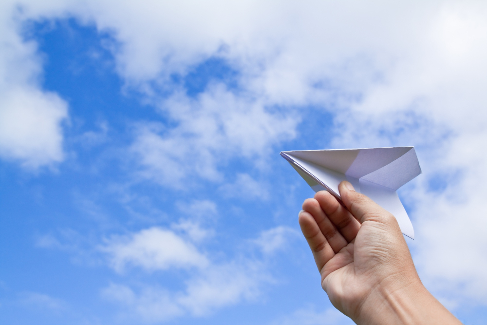 paper airplane flying in the clouds